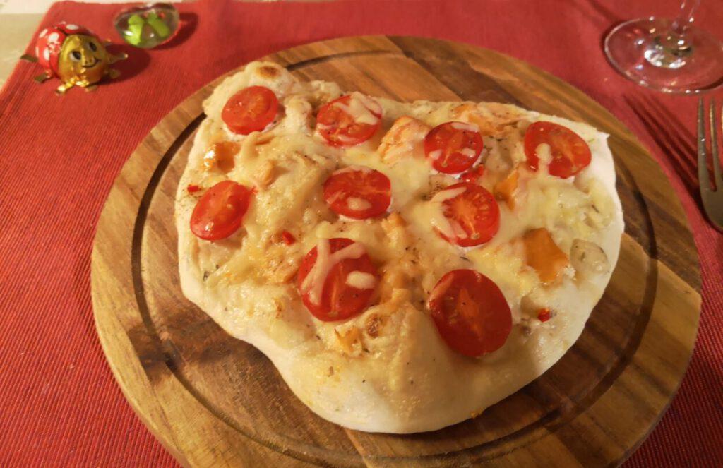 Pizzateig belegt mit Frischkäse, Stremellachs und Kirschtomaten